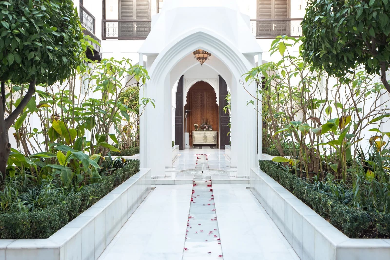Riad Elisa white marble patio with Moorish arches and rose petals